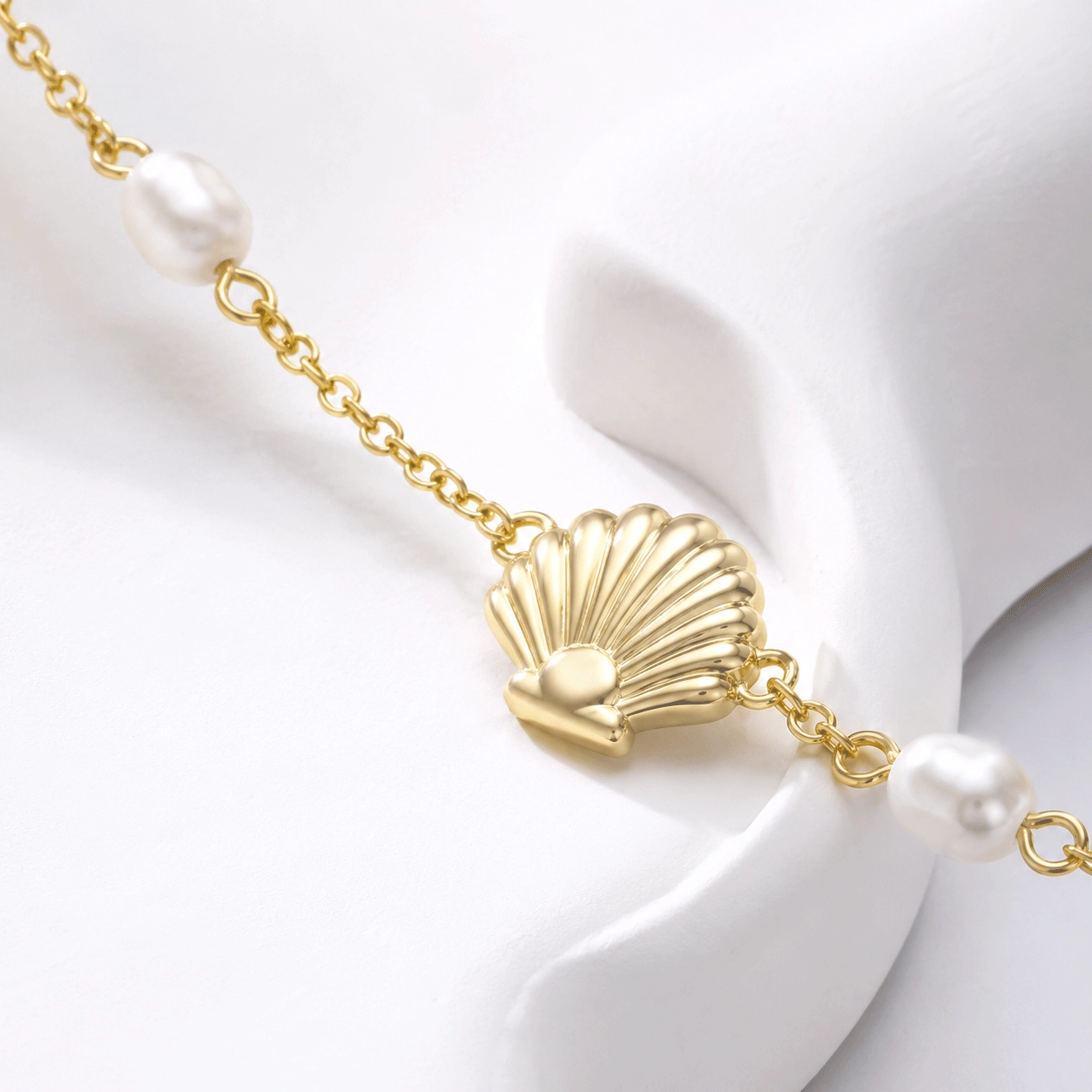 A custom gold-tone shell necklace with freshwater pearls shown in a professional product display - Zhefan Jewelry